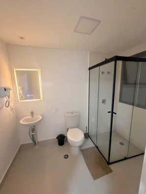 A bathroom with a sink, toilet, and glass-enclosed shower.