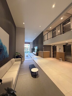 A modern lobby with a sofa, a round table, and a reception desk.