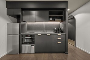 Eine kompakte Küche mit Backofen, Kühlschrank und Kaffeemaschine.