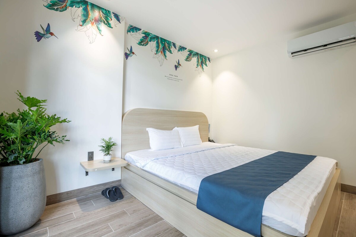 Ein modernes Schlafzimmer mit einem hölzernen Bett, einem Nachttisch, einer Topfpflanze und einer Wandmalerei.