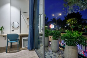 A modern room with a glass door leading to a balcony, a round mirror, and a blue chair. - Bin Bin Hotel 1 - Near RMIT Univerisity (Ho Chi Minh City)