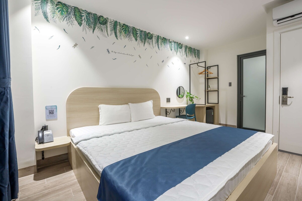 Ein Hotelzimmer mit Bett, Nachttisch, Schreibtisch mit Stuhl, Spiegel und Kleiderschrank.
