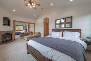 A bedroom with a large bed, a fireplace, a ceiling fan, and a mirror. - 4BR Tahoe Donner retreat with fireplace, deck, HOA access- Chatterjee (Truckee)