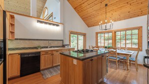Una cocina con armarios de madera, lavavajillas, estufa y un comedor con mesa y sillas.