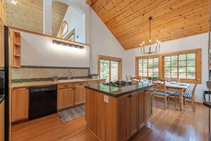 A kitchen with wooden cabinets, a dishwasher, a stove, and a dining area with a table and chairs. - 4BR Tahoe Donner retreat with fireplace, deck, HOA access- Chatterjee (Truckee)
