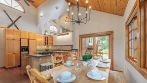 Una cocina amplia con armarios de madera, una isla central y un comedor preparado para seis personas, con vajilla blanca.