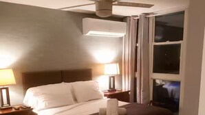 Et hotelværelse med en seng, to sengeborde, en loftsvifte og et vindue.