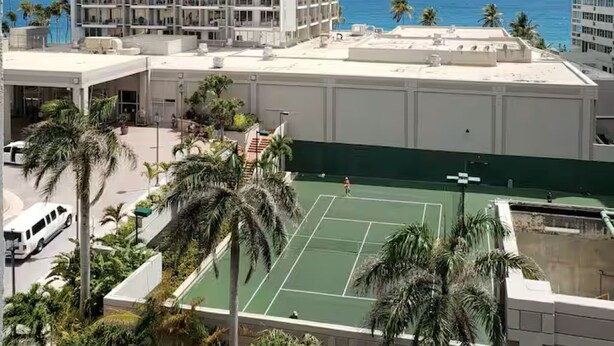 Et Marriott hotel med tennisbane og palmer.