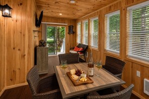 Ein mit Holzpaneelen verkleideter Raum mit einem für zwei Personen gedecktem Esstisch, der eine Weinflasche, Gläser und eine Käseplatte zeigt.
