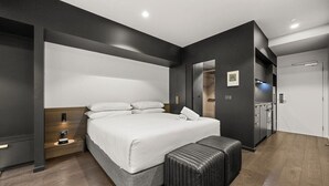 Une chambre moderne avec un grand lit, des tables de chevet, un banc et une armoire.