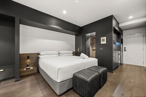 Ein modernes Schlafzimmer mit einem großen Bett, Nachttischen, einer Bank und einem Kleiderschrank.