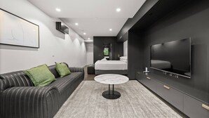 Ein modernes Schlafzimmer mit Bett, Fernseher und einer Sitzecke.
