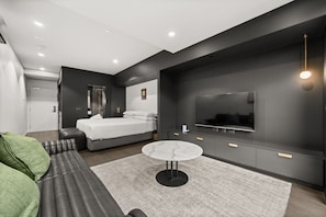 A modern bedroom with a bed, a TV, a sofa, and a small table. - Modern Studio w/ Secure Parking & Haig Park Views! (Braddon)