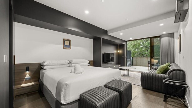 Ein modernes Schlafzimmer mit einem großen Bett, einem Fernseher, einem kleinen Tisch und einer Couch.