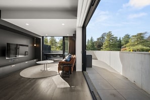 A modern interior with a flat-screen TV, a round dining table, and a sofa. - Stylish Studio w/ Generous Balcony, AC & Parking! (Braddon)