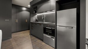 Une cuisine moderne avec des meubles de couleur sombre, un réfrigérateur en acier inoxydable, un four et un four à micro-ondes.