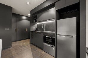 Eine moderne Küche mit dunklen Schränken, einem Edelstahl-Kühlschrank, einem Backofen und einer Mikrowelle.
