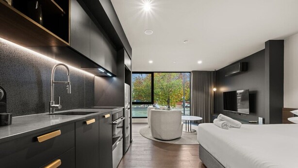 Une chambre d’hôtel moderne dotée d’une cuisine, d’une table à manger ronde et d’un grand lit.