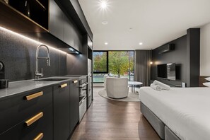 Ein modernes Hotelzimmer mit Küche, einem runden Esstisch und einem großen Bett.