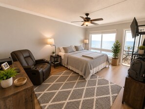 Une chambre à coucher comprenant un lit, une chaise, un bureau, un ventilateur de plafond, une fenêtre avec vue et un téléviseur.
