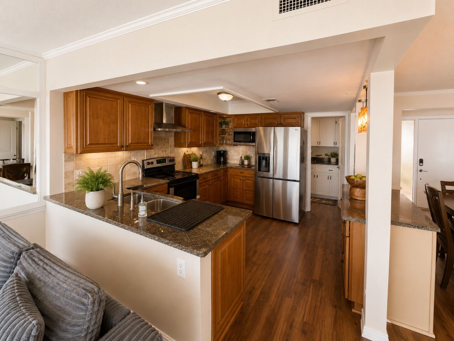 A modern kitchen with wooden cabinets, stainless steel appliances, and a granite countertop.