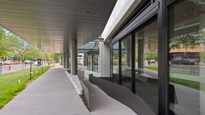 Un paseo techado con diseño arquitectónico moderno, amplios ventanales y una vista despejada de la calle.