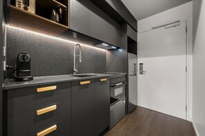 A modern kitchen with a built-in espresso machine, a stainless steel sink, and a compact oven. - Spectacular Studio In Heart Of Braddon w/ Parking! (Braddon)