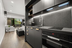 A modern kitchen with a black countertop, stainless steel appliances, and a digital clock displaying 2:21. - Spectacular Studio w/ Haig Park Views & Parking! (Braddon)