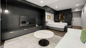 Ein modernes Schlafzimmer mit einem großen Bett, einem Fernseher, einem kleinen runden Tisch und einem begehbaren Kleiderschrank.