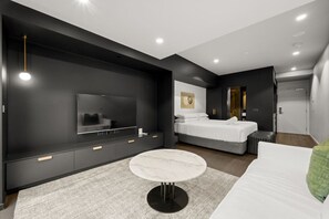 A modern bedroom with a large bed, a TV, a small round table, and a walk-in closet. - Spectacular Studio w/ Haig Park Views & Parking! (Braddon)