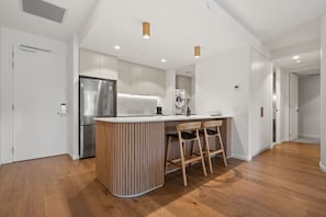 Eine moderne Küche mit einer zentralen Kochinsel, Holzstühlen und einem Edelstahl-Kühlschrank.