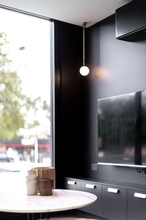 Eine moderne Küche mit großem Fenster, einer Pendelleuchte und einem integrierten Fernseher.