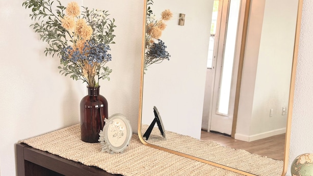 A mirror reflecting a room with a vase of flowers, a framed picture, and a globe on a textured mat. - 2-bedroom/2bath condo near downtown Spokane (Spokane)