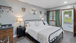 Een slaapkamer met een bed, nachtkastjes, een bureau, een stoel en een raam met gordijnen.