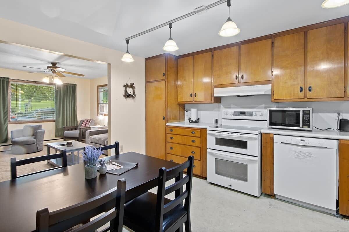 Une cuisine moderne avec des meubles en bois, un coin repas comprenant une table et des chaises, et un ventilateur de plafond.