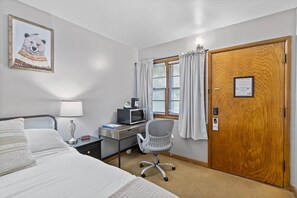 Una habitación de hotel con cama, escritorio, silla y puerta.