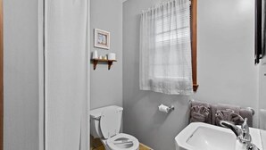 Et badeværelse med toilet, vask og bruseforhæng.