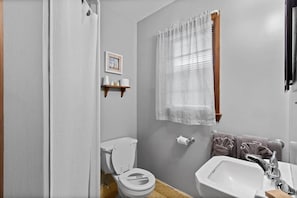A bathroom with a toilet, sink, and shower curtain.