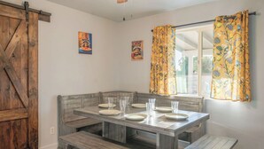 A dining area with a wooden bench seating, a table with plates and glasses, and a window with curtains.