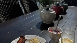 Uma mesa com itens de café da manhã, um copo de suco e vasos decorativos.