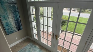 Quarto com uma grande porta de vidro que dá para área externa, um tapete azul com textura e um quadro na parede.