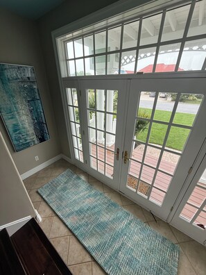 A room with a large glass door leading to an outdoor area, a blue textured rug, and a painting on the wall. - Spacious 4-bedroom house in Ocean Pines (Ocean Pines)