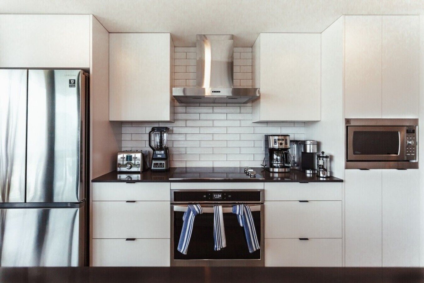 A modern kitchen with a stainless steel refrigerator, a coffee maker, a microwave, and a toaster.