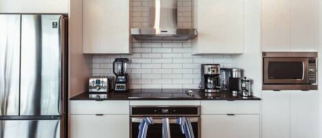 A modern kitchen with a stainless steel refrigerator, a coffee maker, a microwave, and a toaster.