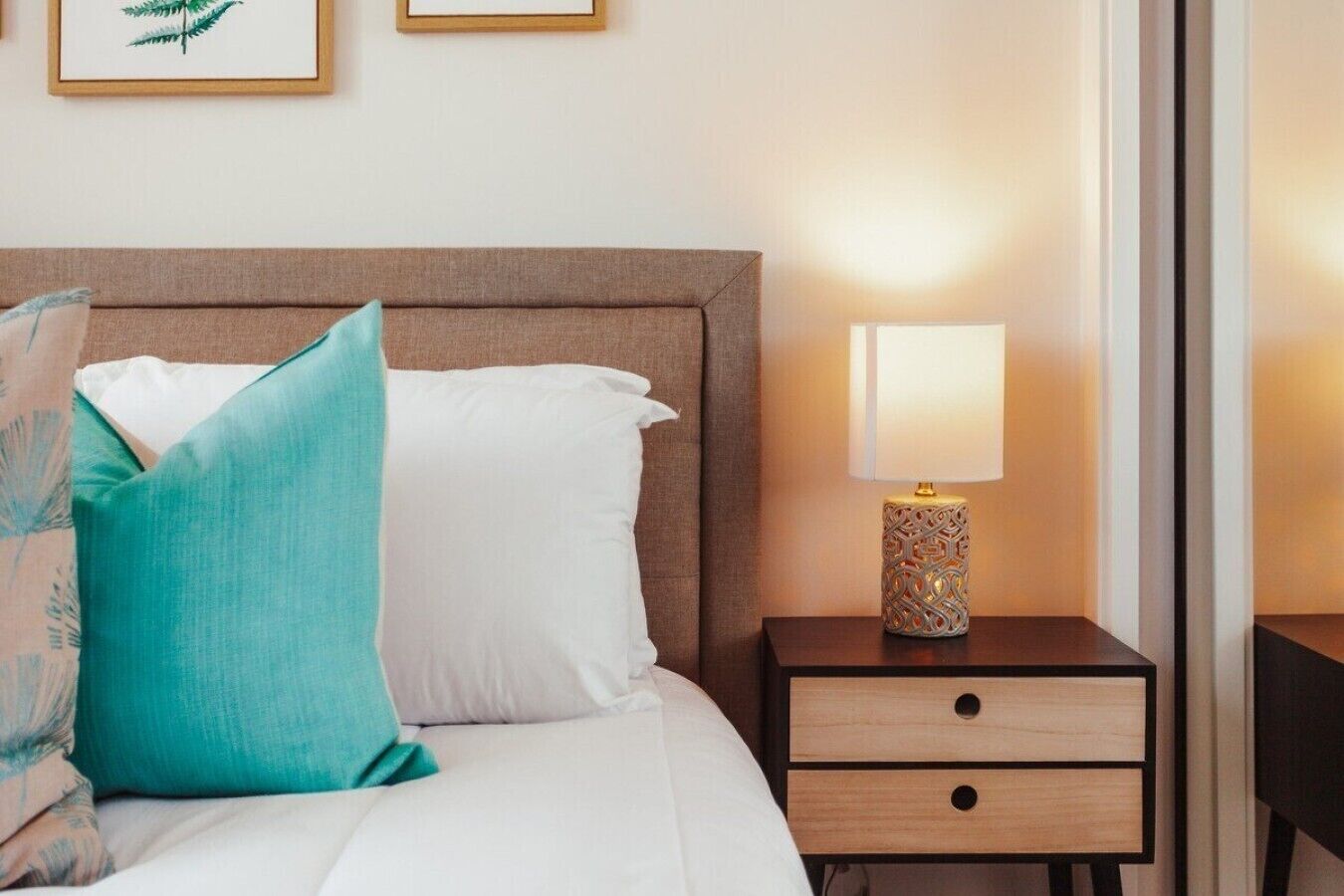 A hotel room with a bed, a nightstand with a lamp, and a wall-mounted picture.