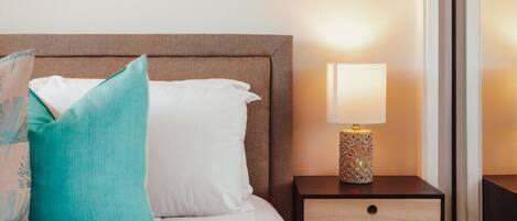 A hotel room with a bed, a nightstand with a lamp, and a wall-mounted picture.