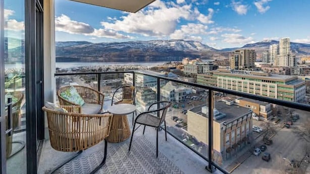 A balcony with wicker furniture and a city view.