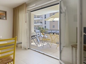 Ein Zimmer mit einer Schiebetür, die auf einen Balkon mit Stühlen und einem Tisch führt.