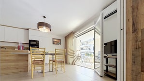 A modern kitchen with wooden cabinets, a dining area with two chairs, a pendant light, and a view of the outside. - L'Instant Azur, Beach, on foot, Clim Garage (Fréjus)