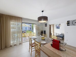 A modern living room with a dining area, a sofa, a TV, and a large window with curtains. - L'Instant Azur, Beach, on foot, Clim Garage (Fréjus)